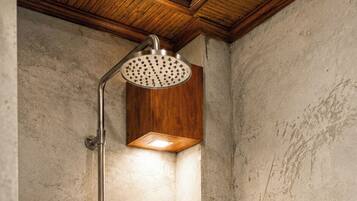 A shower with a handheld showerhead and a wall-mounted control panel.