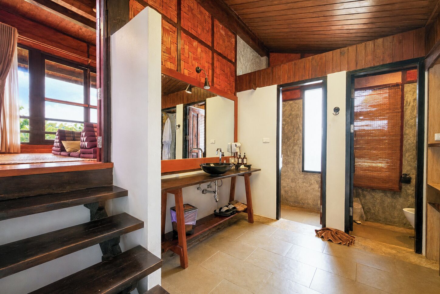 Una cocina moderna con una escalera de madera, un lavamanos y un ventanal con vistas a un jardín.