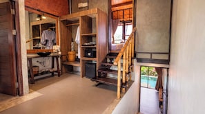 A wooden interior with a kitchen area, a staircase, and a view of a swimming pool. - Alama Sea Village Resort (Ko Lanta)