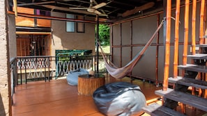 A hammock hanging between bamboo poles, a wooden deck, and a metal railing. - Alama Sea Village Resort (Ko Lanta)