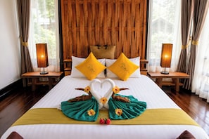 A hotel room with a large bed, two bedside tables with lamps, and a wooden headboard. - Alama Sea Village Resort (Ko Lanta)