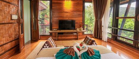 A wooden room with a bed, a television, and large windows.