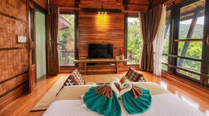A wooden room with a bed, a television, and large windows. - Alama Sea Village Resort (Ko Lanta)