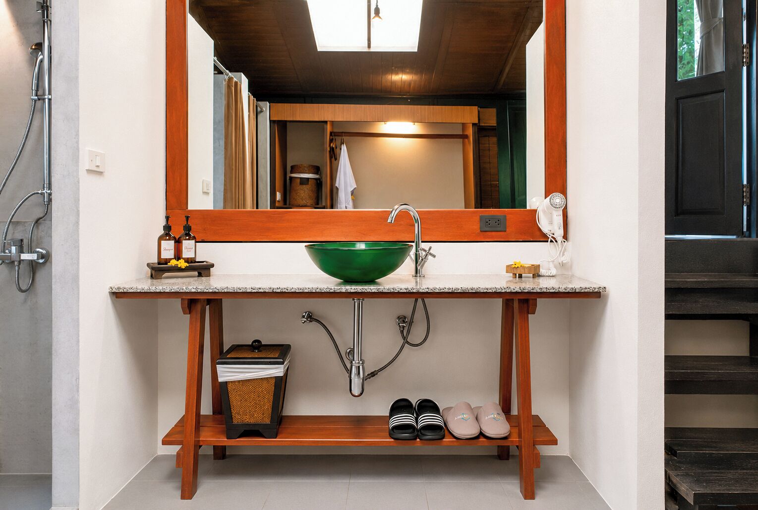 A bathroom with a wooden vanity, a green basin, and a mirror above it.