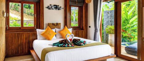 A wooden-framed bedroom with a bed, two pillows, a wall-mounted artwork, and a view of greenery through the window.