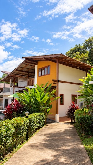 A building with a covered walkway, surrounded by lush greenery and a clear sky.