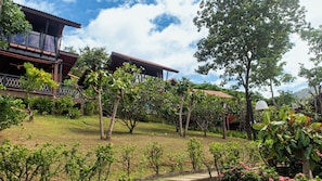 A residential area with a house featuring a balcony, surrounded by lush greenery and trees. - Alama Sea Village Resort (Ko Lanta)