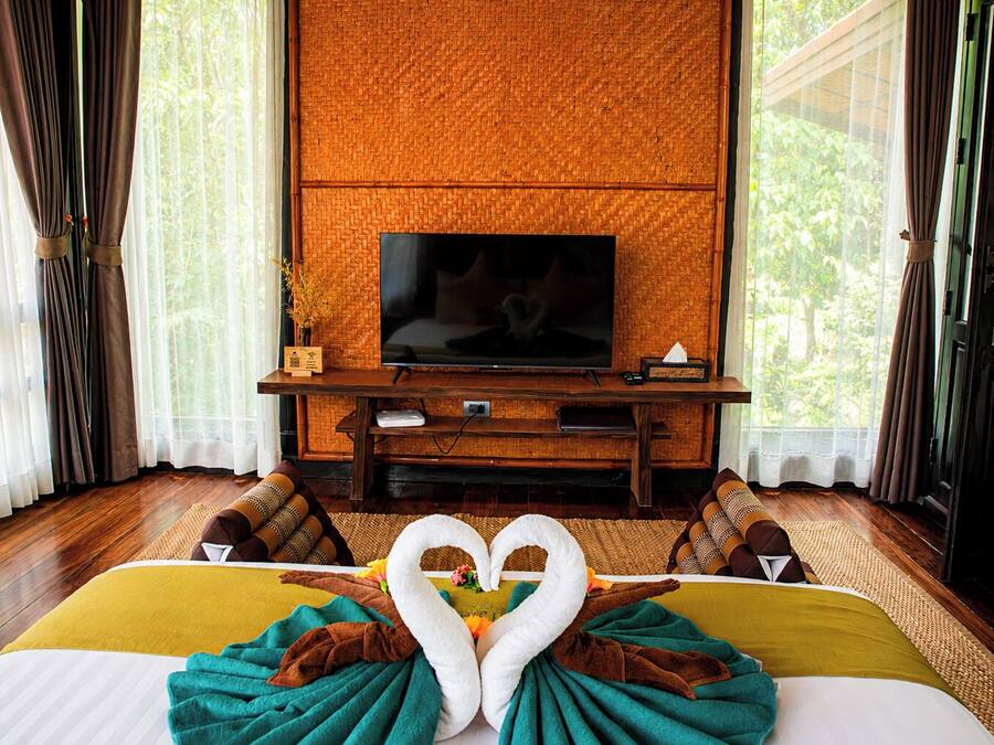 Quarto de hotel com cama, televisão e vista para o verde lá fora.