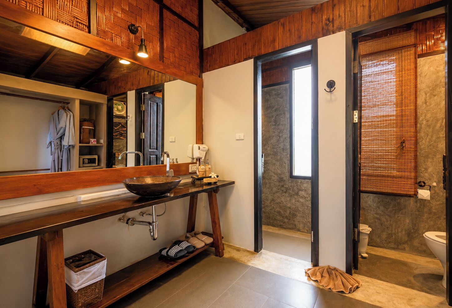 A bathroom with a wooden vanity, a sink, a mirror, and a toilet.