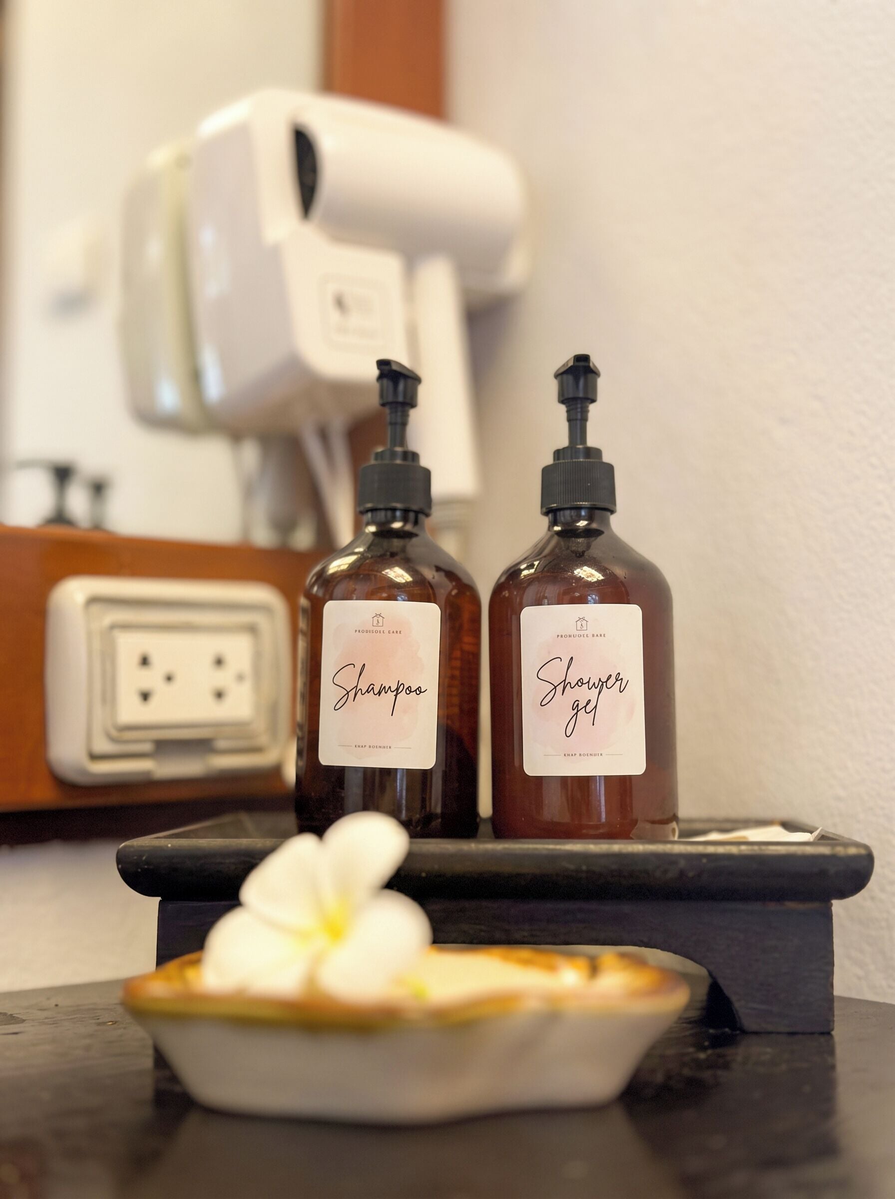 Zwei Flaschen Shampoo und Duschgel auf einer Ablage mit einer weißen Blume.
