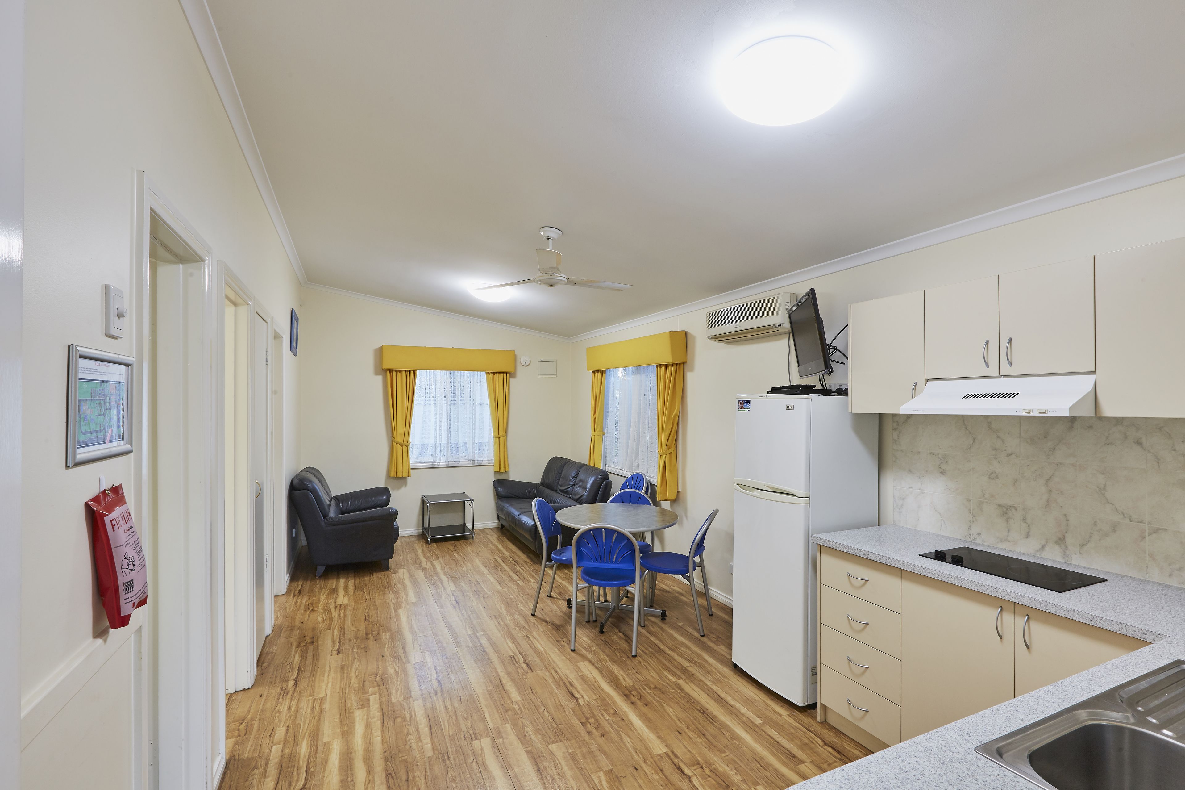 A compact kitchen with a sink, stove, and cabinets. There is a dining area with a table and chairs, and a sofa.