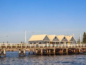 Un muelle con una hilera de edificios, incluyendo un restaurante llamado "Buselton Jetty".