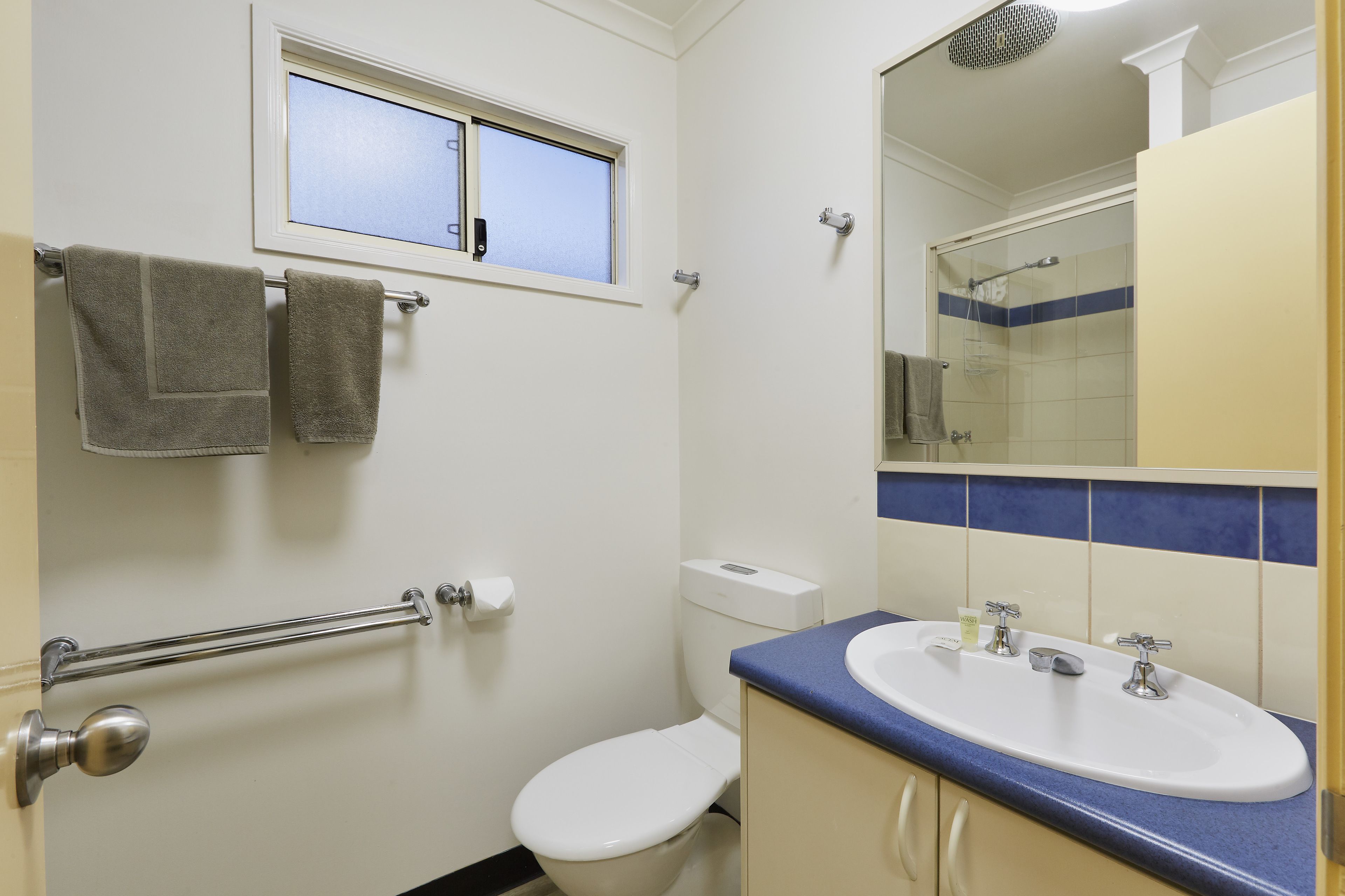 Un baño con inodoro, lavamanos y ventana.
