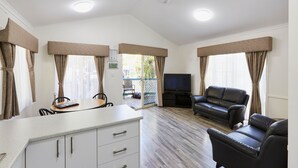 A spacious living area with a dining table, a sofa, and a TV. - Discovery Parks - West Busselton (West Busselton)