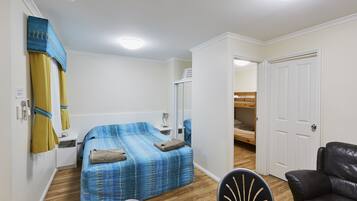 Una habitación con cama, una silla, una mesa, un armario y una puerta.