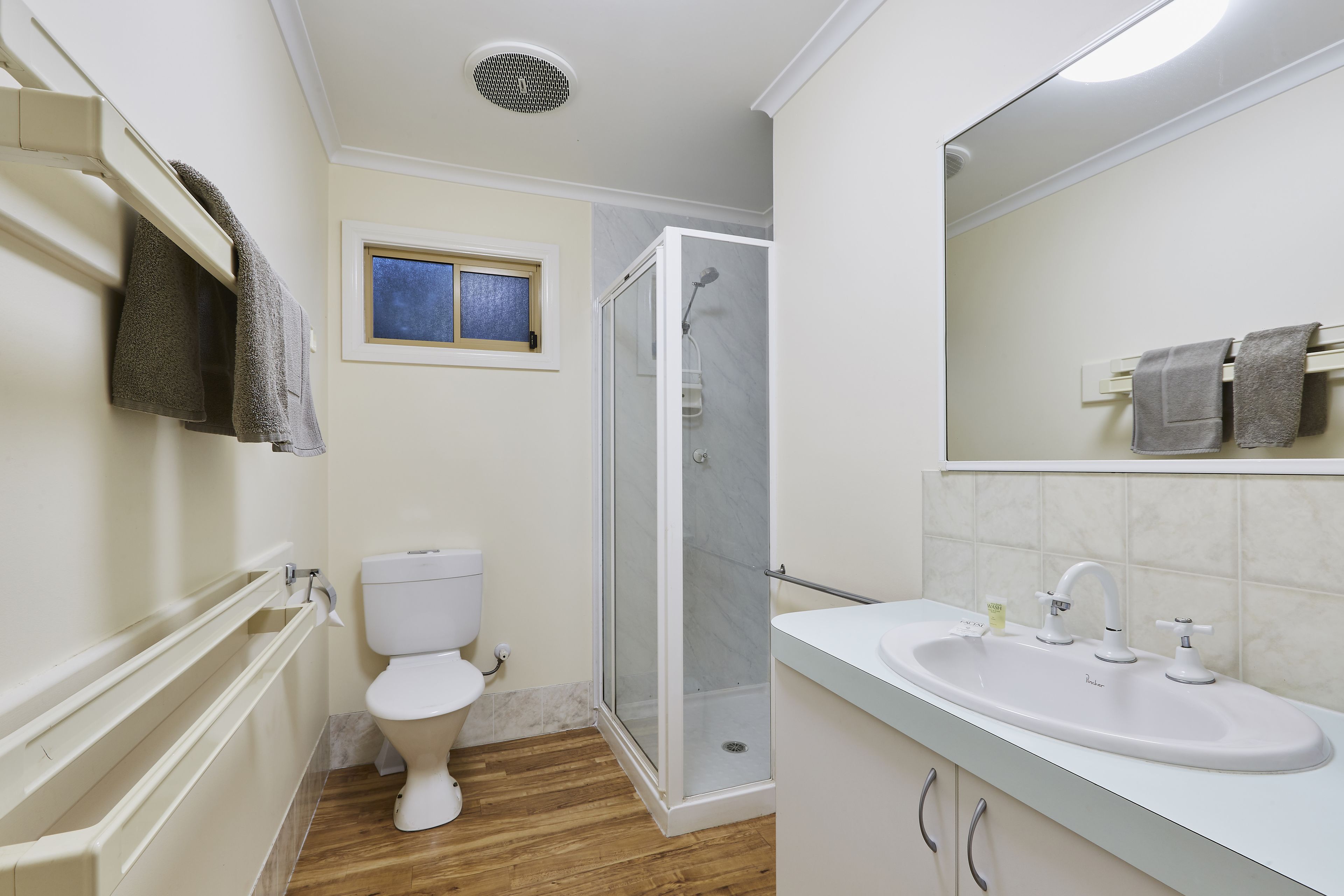 Un baño con inodoro, ducha, lavamanos y ventana.