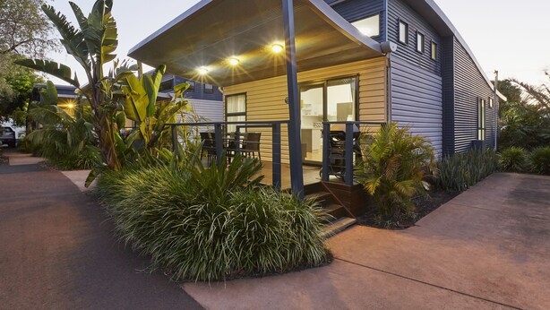 A modern house with a covered porch, a visible kitchen area, and lush tropical landscaping. - Discovery Parks - West Busselton (West Busselton)