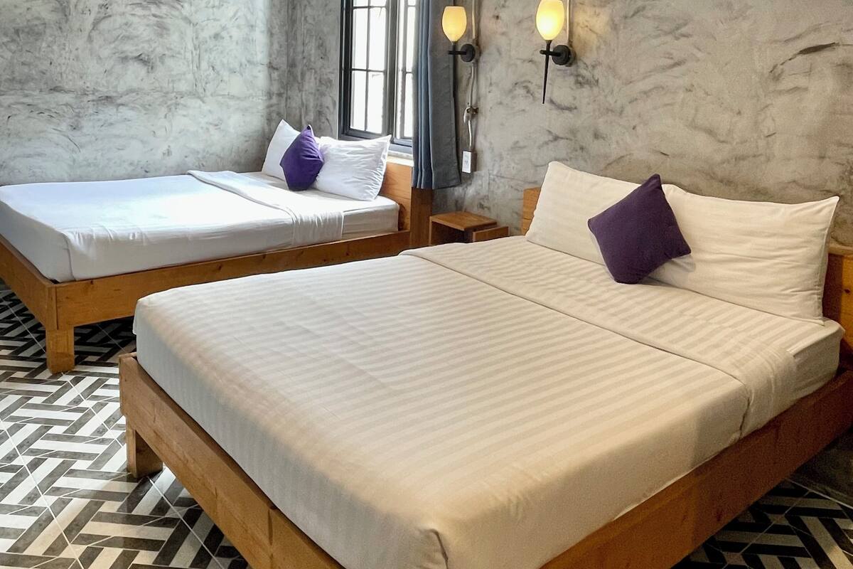 A hotel room with two wooden beds, a marble wall, and a patterned floor.