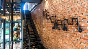 A staircase leading to a second floor with a brick wall and a sign with Chinese characters. - Na Siam Guesthouse (Phuket)
