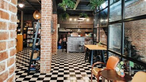 A cafe with a checkered floor, brick walls, and hanging plants. - Na Siam Guesthouse (Phuket)