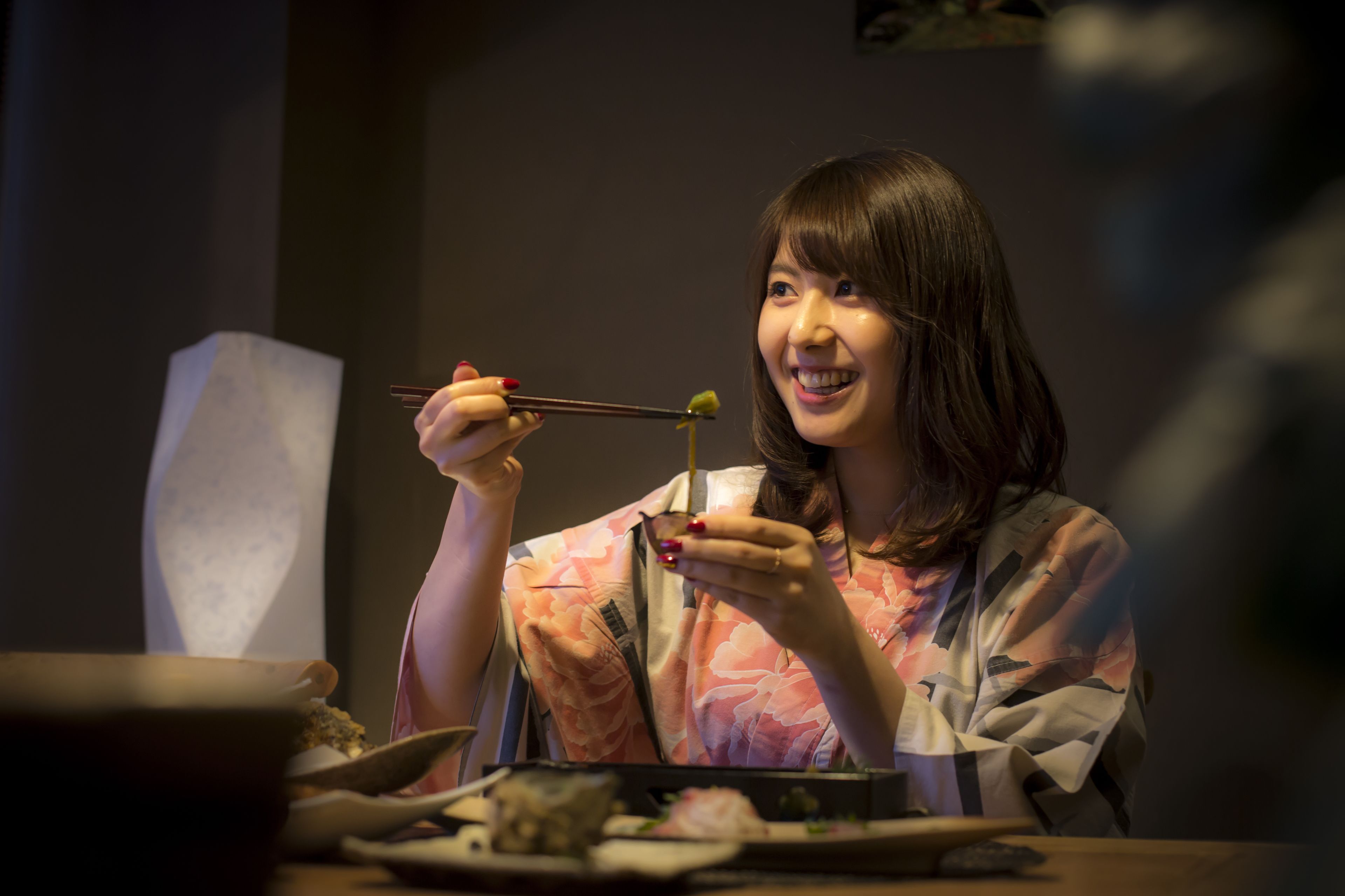 A person sitting at a table with chopsticks and a bowl, likely in a dining setting.