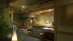 Ein traditionelles japanisches Interieur mit Tatami-Böden, einer Rezeption und einer Holzbalkendecke mit dekorativen Elementen.
