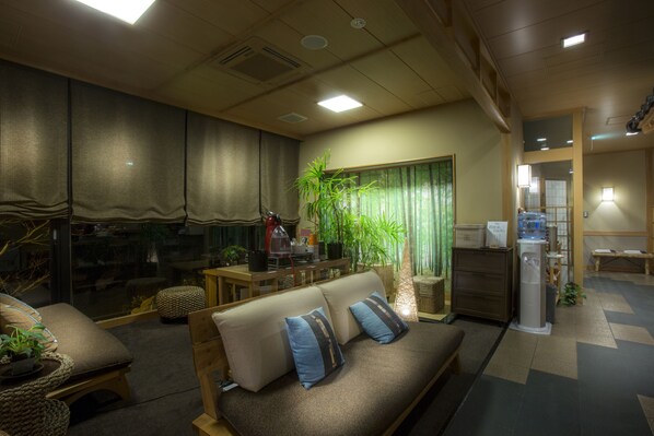A cozy hotel room with a sofa, a dining table, a plant, and a small kitchen area. - Jukaitei (Kyotango)