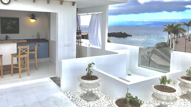A modern kitchen with a bar area, white walls, and a view of the sea. - Rok Plaza - Only Adults (Guia de Isora)