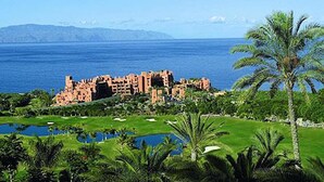 A coastal resort with a large body of water, a golf course, and a prominent building with a mountainous backdrop. - Rok Plaza - Only Adults (Guia de Isora)