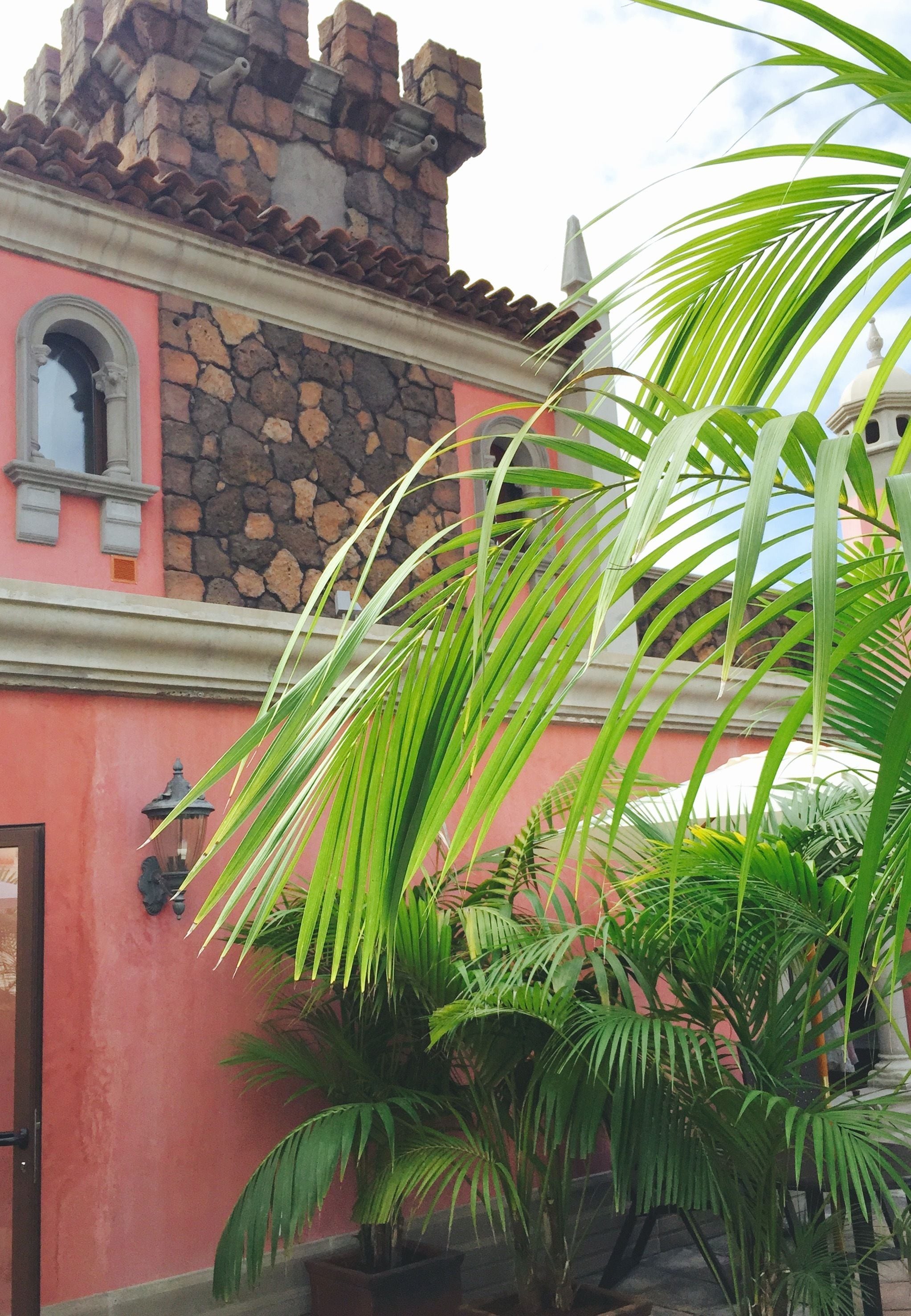 Um edifício com fachada de pedra, uma parede rosa e uma janela com arco decorativo.