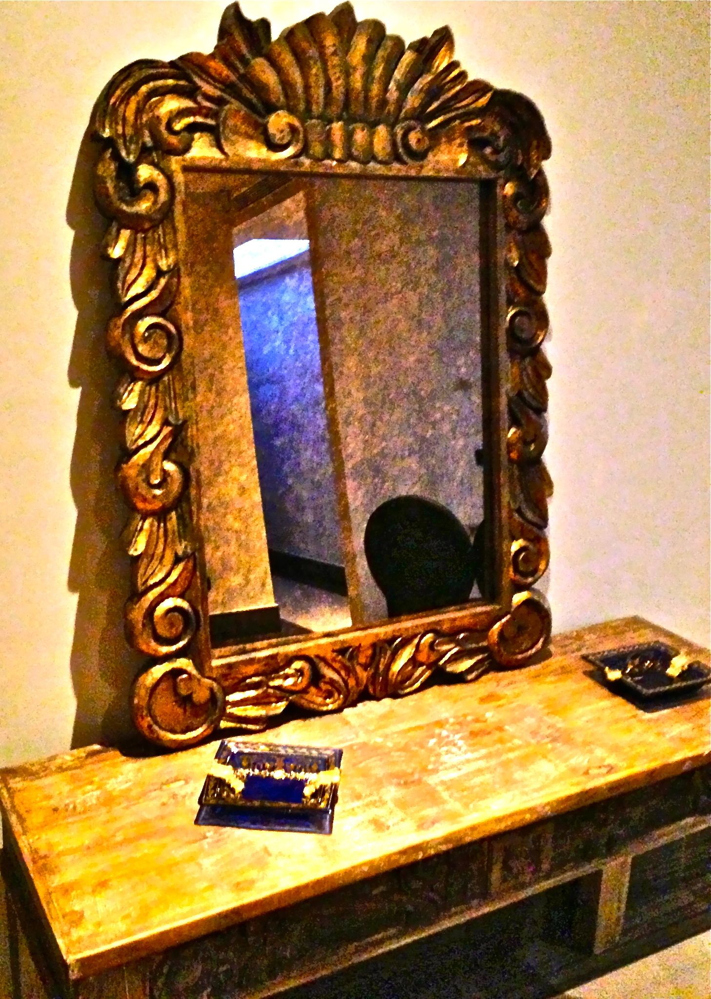 A mirror with an ornate frame on a wooden surface.
