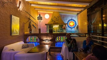 Un rincón acogedor de bar con asientos, una barra y una pared decorativa con un letrero de neón.