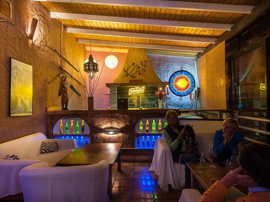 Un rincón acogedor de bar con asientos, una barra y una pared decorativa con un letrero de neón.
