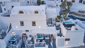 Una terraza con jacuzzi, mobiliario exterior y vistas de los edificios circundantes.