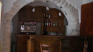A rustic bar area with stone arches, wooden shelves with bottles, and a coffee machine. - Art Hotel (Villetta Barrea)