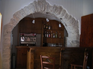 A rustic bar area with stone arches, wooden shelves with bottles, and a coffee machine. - Art Hotel (Villetta Barrea)