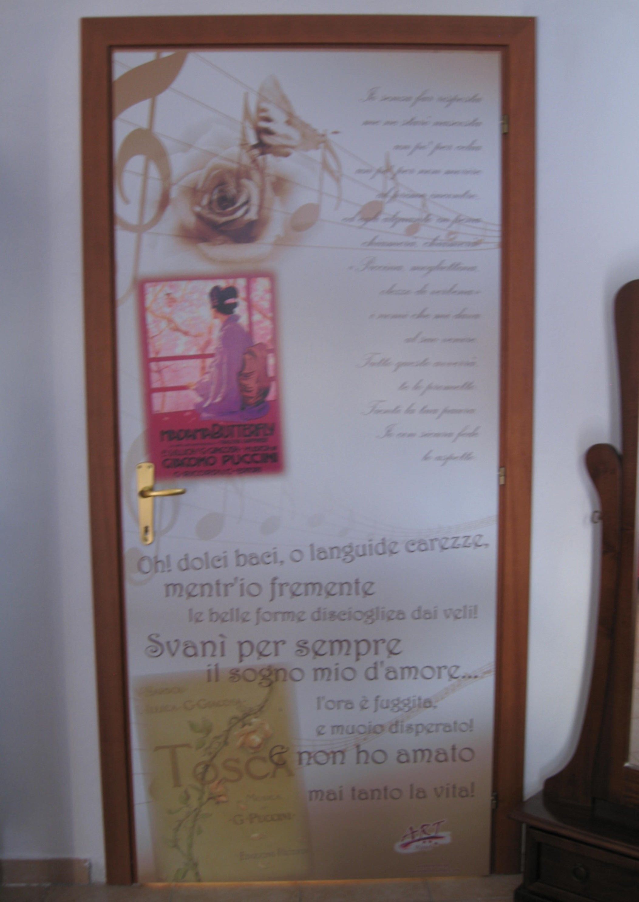 Una puerta con un panel decorativo que muestra una rosa, un cartel y texto escrito a mano.