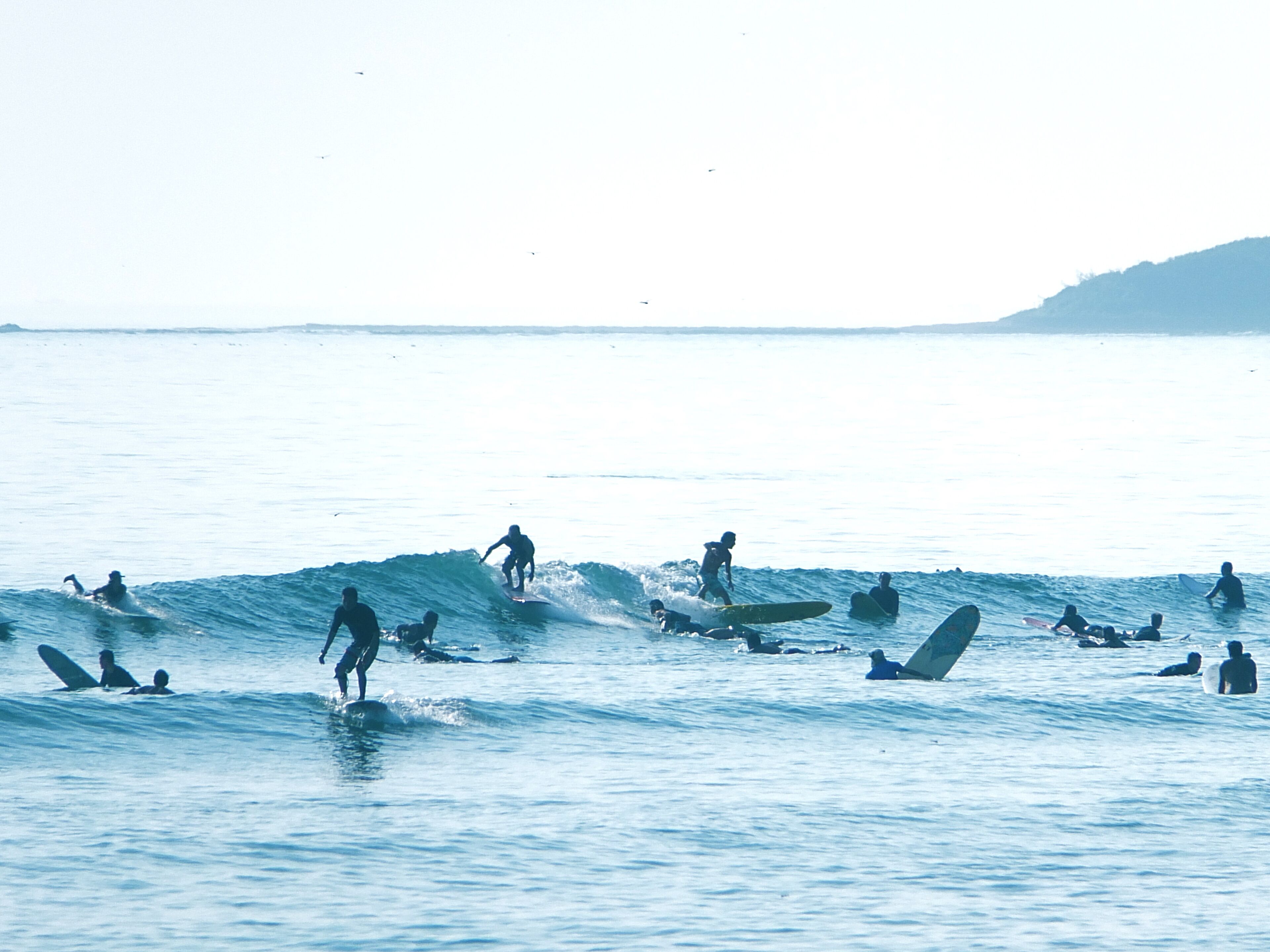 A beach with multiple surfers and swimmers in the water.