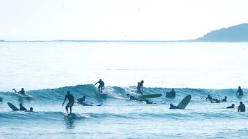 A beach with multiple surfers and swimmers in the water.