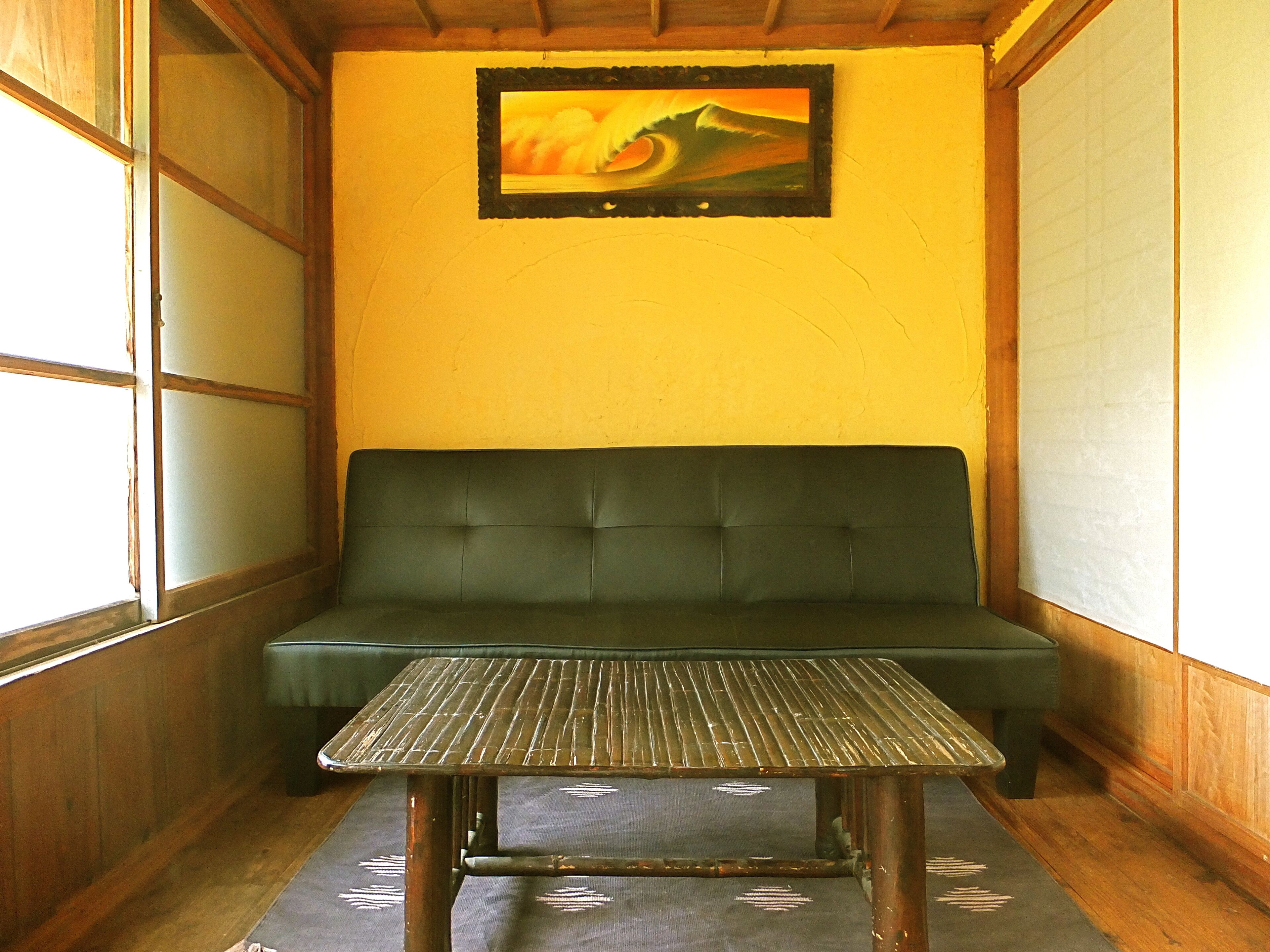 A room with a green sofa, a small table, and a painting on the wall.