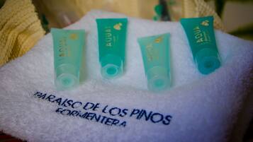 Cuatro tubos de color aguamarina de AQUA sobre una toalla blanca con texto bordado.
