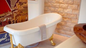 Una vasca da bagno freestanding bianca con dettagli dorati e un asciugamano appoggiato.