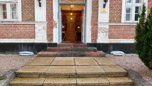 A brick building with a staircase leading to a door marked with the number 14. - Boutique Hotel Postgården (Holsted)