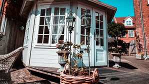 A white building with large windows and two ornate street lamps. - Boutique Hotel Postgården (Holsted)