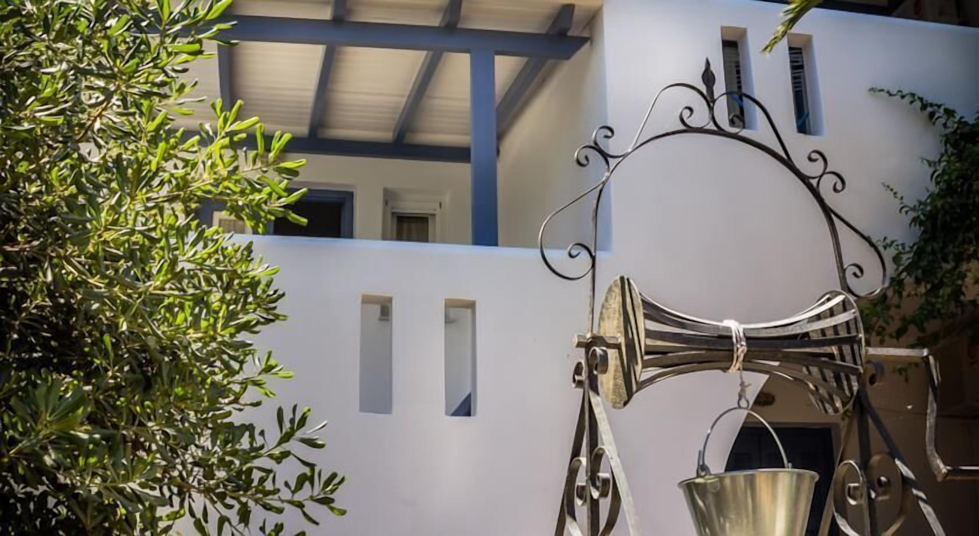 A white building with a metal gate and a metal bucket hanging on it.