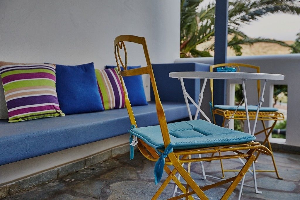 A blue outdoor seating area with a sofa and two wicker chairs with blue cushions.