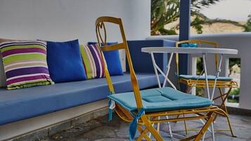 A blue outdoor seating area with a sofa and two wicker chairs with blue cushions.