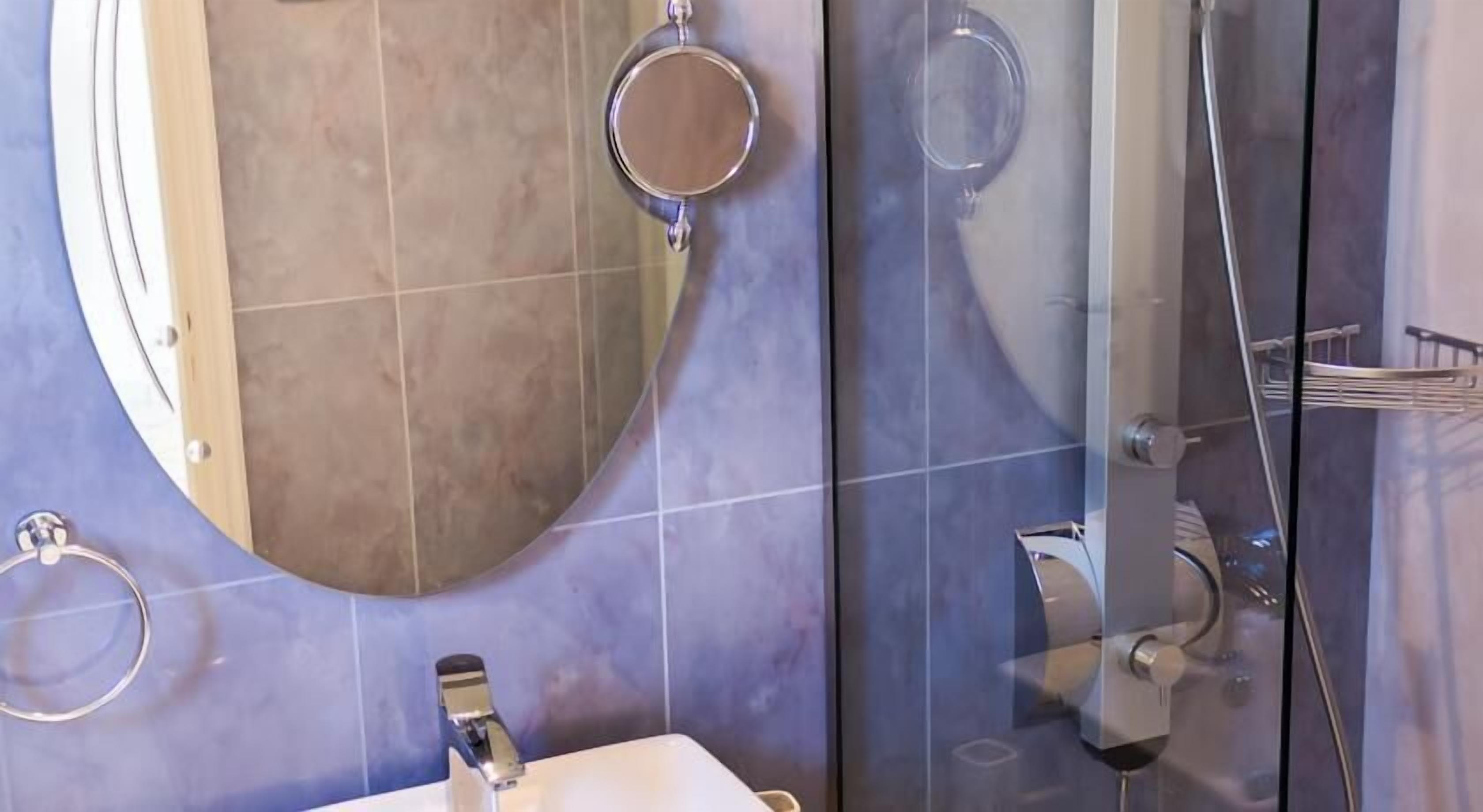 Une salle de bain avec un grand miroir, un lavabo et un espace douche.