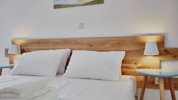 A neatly made bed with white linens and pillows, a wooden headboard, and two bedside tables with lamps.