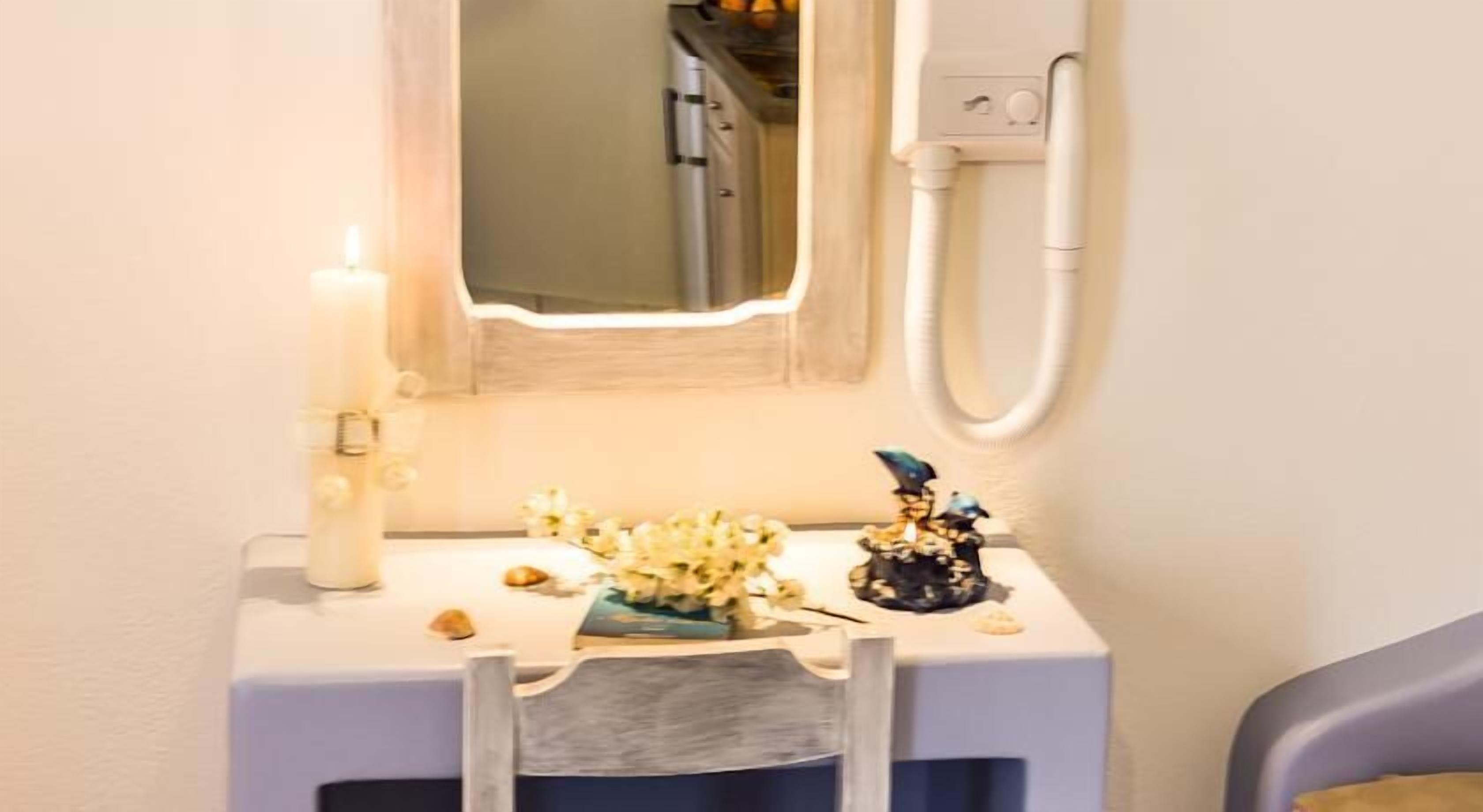 Een klein kaptafeltje met spiegel, een kaars en een decoratief object.